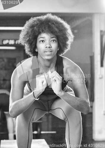 Image of black female athlete is performing box jumps at gym