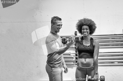 Image of black woman doing bicep curls with fitness trainer