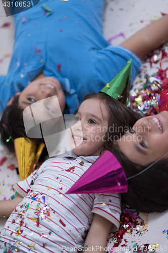 Image of kids  blowing confetti while lying on the floor