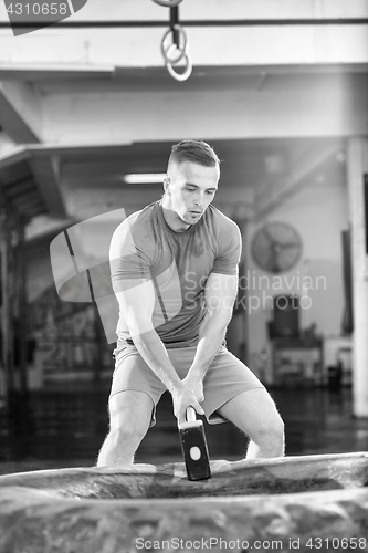 Image of man workout with hammer and tractor tire