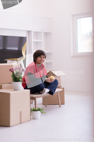 Image of boy sitting on the table with cardboard boxes around him