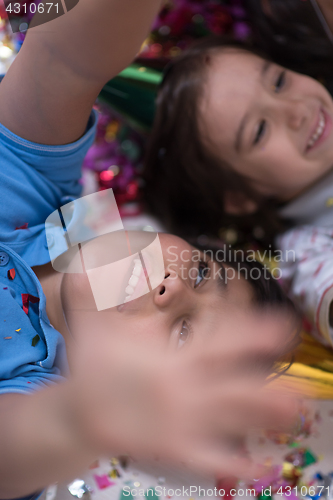 Image of kids  blowing confetti while lying on the floor