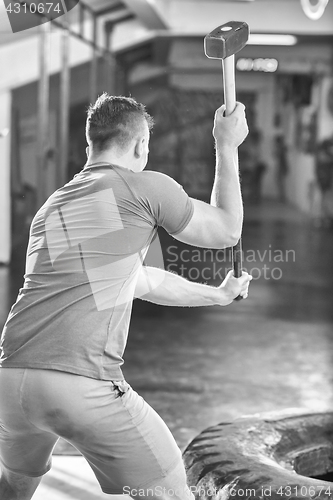 Image of man workout with hammer and tractor tire