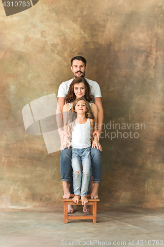 Image of Pregnant mother with teen daughter and husband. Family studio portrait over brown background