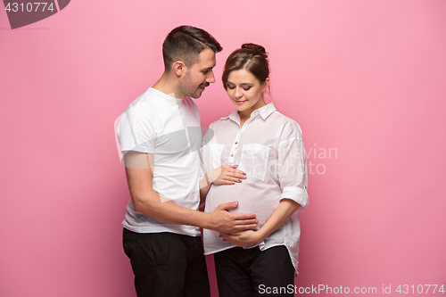 Image of Handsome man is listening to his beautiful pregnant wife\'s tummy and smiling