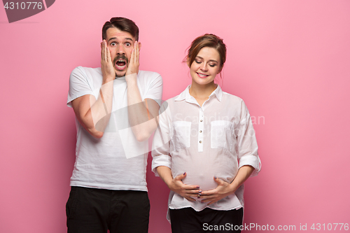 Image of The funny surprised handsome man and his beautiful pregnant wife\'s tummy