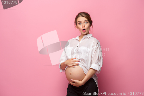 Image of Young beautiful pregnant woman standing on pink background