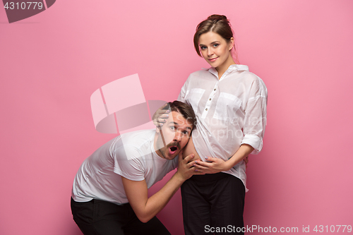 Image of Handsome man is listening to his beautiful pregnant wife\'s tummy and smiling