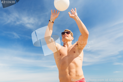 Image of young man with ball playing volleyball on beach