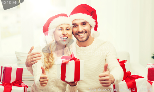 Image of happy couple with christmas gifts and thumbs up