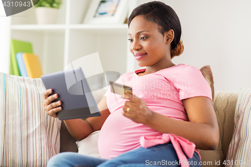 Image of pregnant woman with tablet pc and credit card