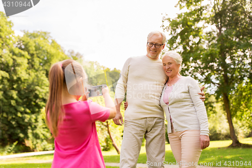 Image of granddaughter photographing grandparents at park