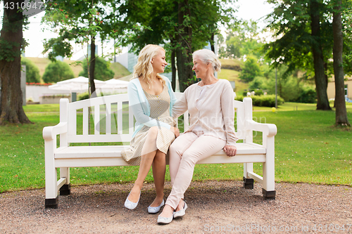 Image of daughter with senior mother hugging on park bench