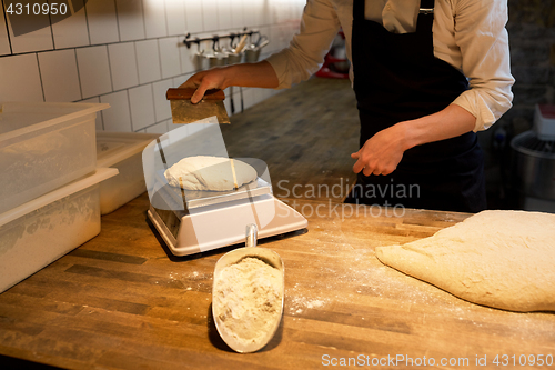 Image of baker weighing bread dough on scale at bakery