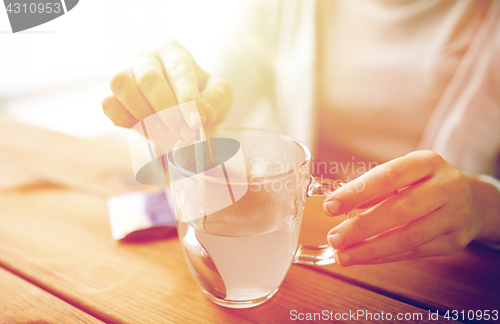 Image of woman stirring medication in cup of water