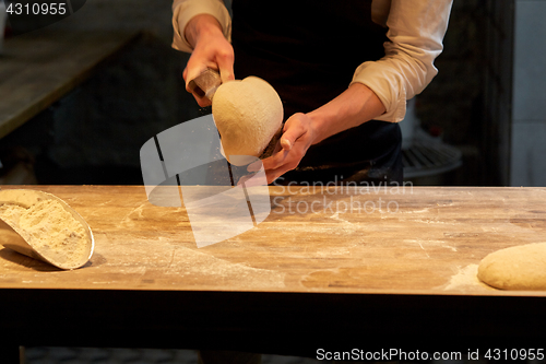 Image of baker portioning dough with bench cutter at bakery