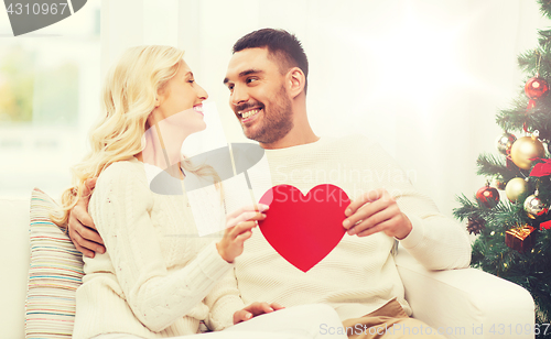 Image of happy couple with red heart at home for christmas