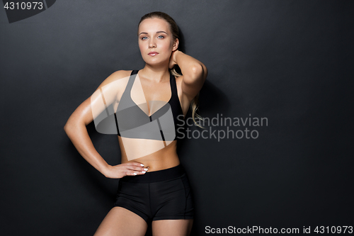 Image of young woman in black sportswear posing in gym