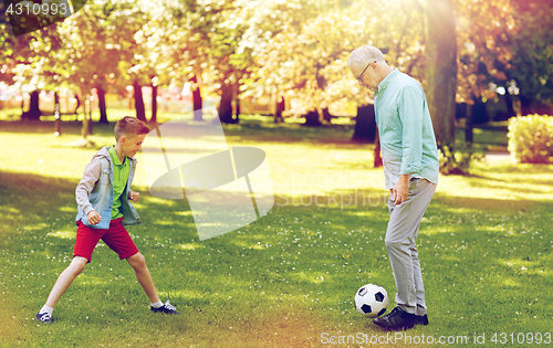 Image of old man and boy playing football at summer park