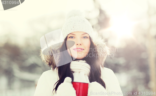 Image of happy young woman with tea cup outdoors in winter