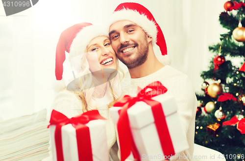 Image of happy couple at home with christmas gift boxes