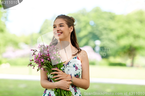 Image of happy young woman with flowers in summer park