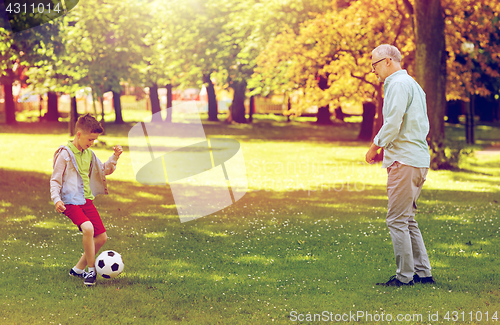 Image of old man and boy playing football at summer park