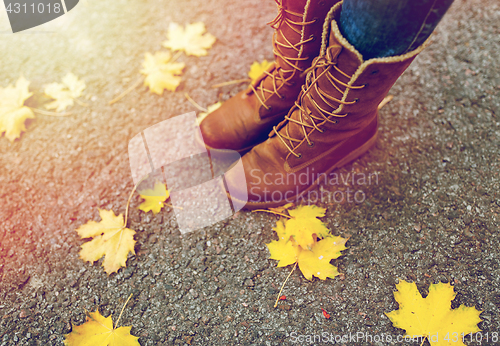 Image of female feet in boots and autumn leaves