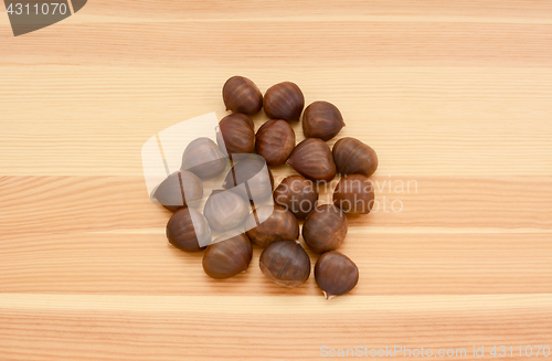 Image of Sweet chestnuts in shells on wood