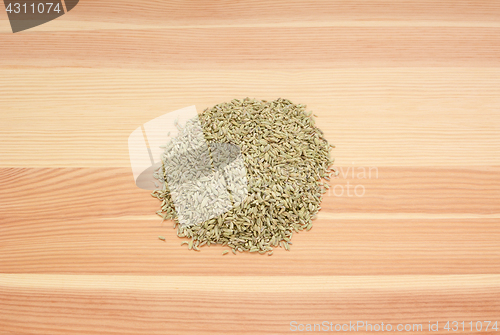 Image of Heap of dried fennel seeds on wood