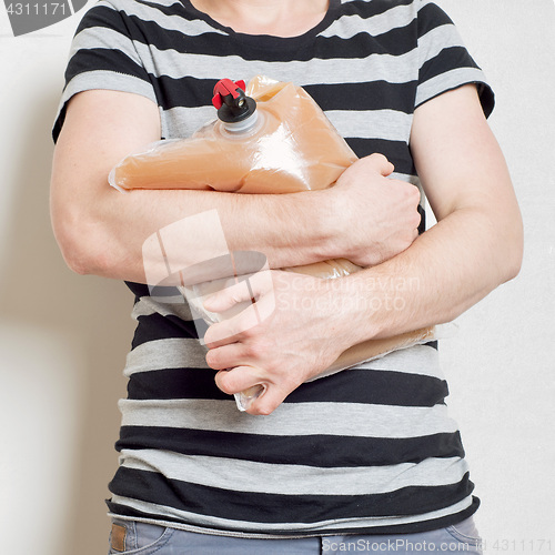 Image of Man holding plastic bag with tap full of apple juice