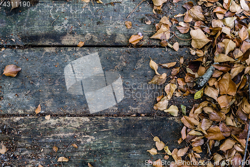 Image of Background with old wooden table and yellow autumnal leaves