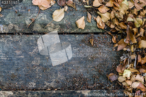 Image of Background with old wooden table and yellow autumnal leaves