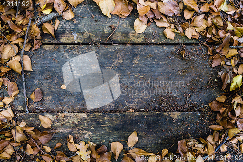 Image of Background with old wooden table and yellow autumnal leaves
