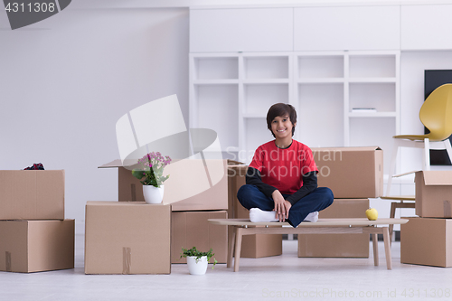 Image of boy sitting on the table with cardboard boxes around him