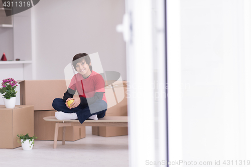 Image of boy sitting on the table with cardboard boxes around him