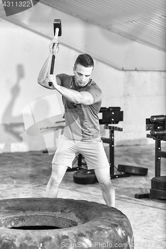 Image of man workout with hammer and tractor tire