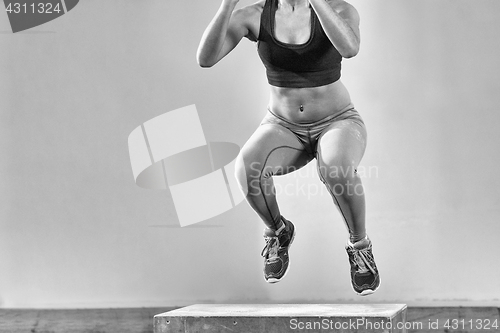 Image of black woman is performing box jumps at gym