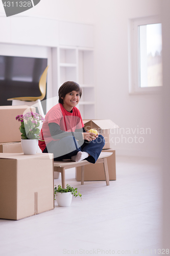 Image of boy sitting on the table with cardboard boxes around him