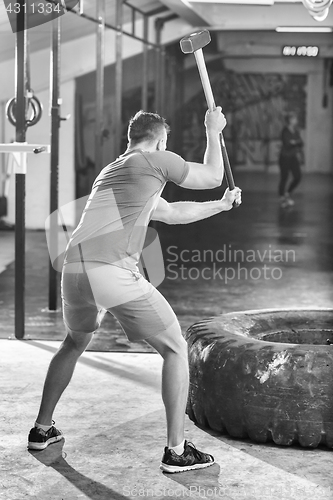 Image of man workout with hammer and tractor tire