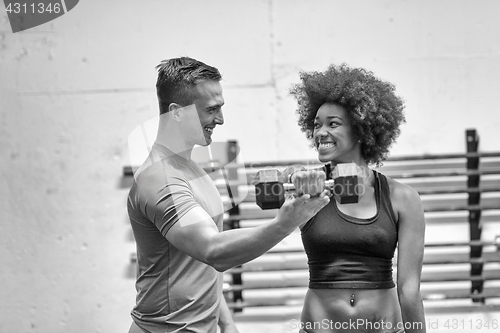 Image of black woman doing bicep curls with fitness trainer