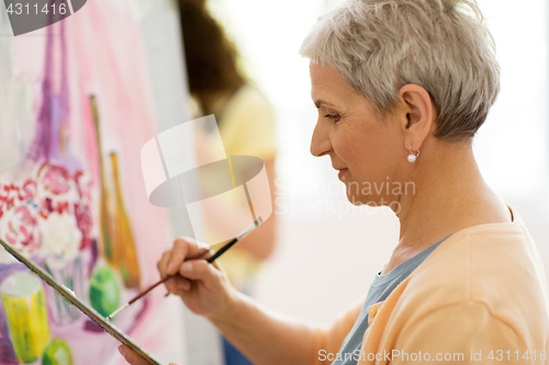Image of senior woman artist painting at art school