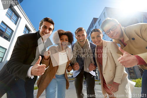 Image of group of people showing thumbs up in city