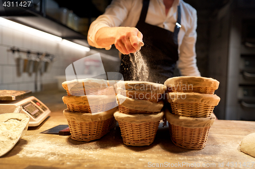 Image of baker with baskets for dough rising at bakery