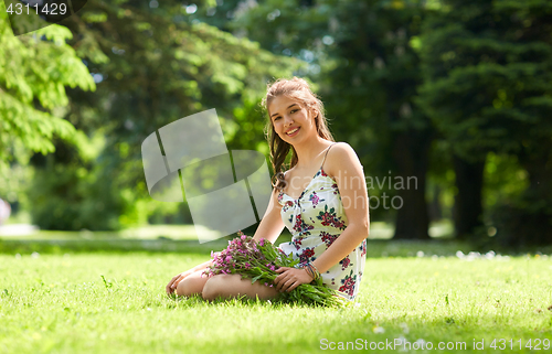 Image of happy young woman with flowers in summer park