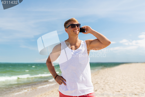 Image of smiling man calling on smartphone on summer beach