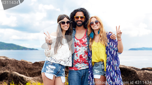 Image of happy hippie friends showing peace on summer beach