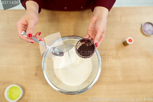 Image of chef hands adding food color into bowl with flour