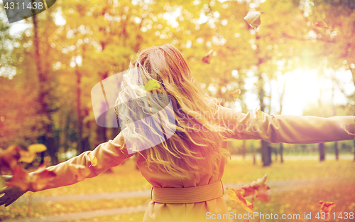 Image of happy woman having fun with leaves in autumn park