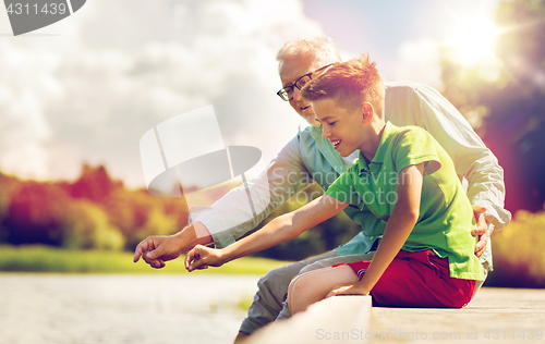 Image of grandfather and grandson sitting on river berth